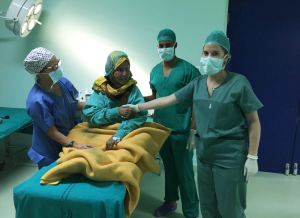 Tres personas saludan a una mujer en el quirófano 