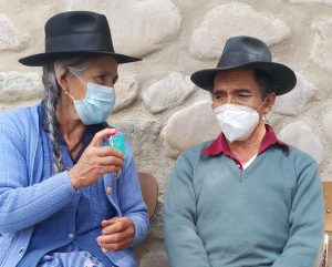 A woman and a man, Martin Gonzales, wearing hats and masks, talking