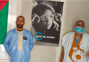 Dos personas en la inauguración de la casa de acogida de Bechar delante de un póster de Ojos del mundo.