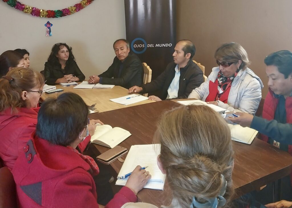 Grup de dones i homes asseguts en una taula durant la reunió de balanç 2023