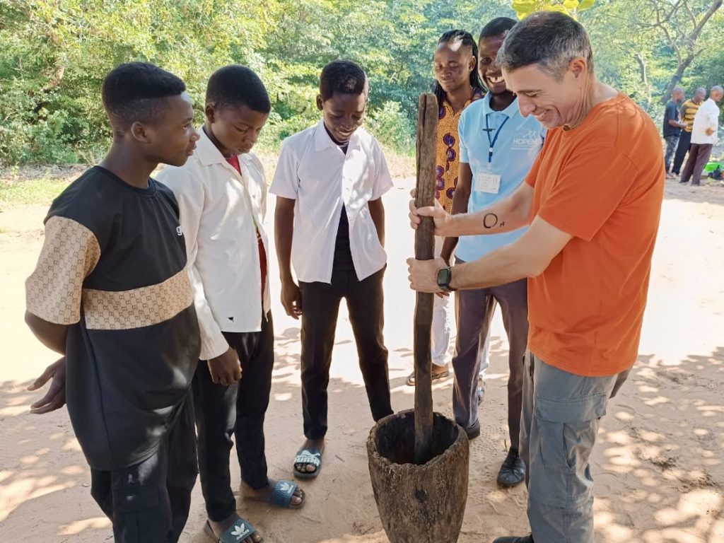 Group of young people with Paco Abril grinding grain